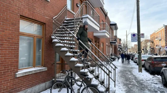 Escalier extérieur métallique typique d'un duplex montréalais en hiver, avec neige et glace visibles sur les marches